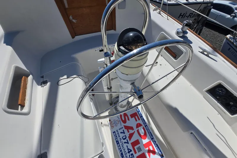 Slide: The Image of 1986 Pearson 303 Sloop cockpit with steering wheel and compass, for sale sign visible. - 25