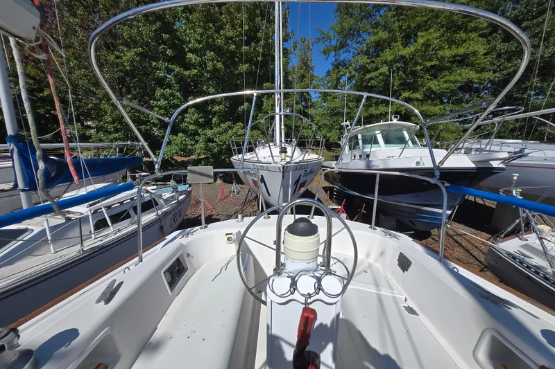 Slide: The Image of 1986 Pearson 303 Sloop sailboat docked among other boats, surrounded by trees. - 27