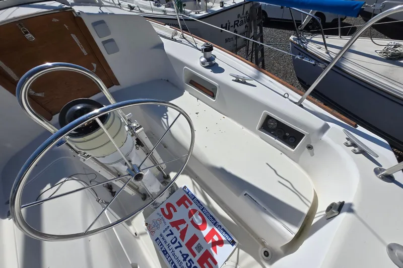 Slide: The Image of 1986 Pearson 303 Sloop cockpit with steering wheel, for sale sign visible. - 32