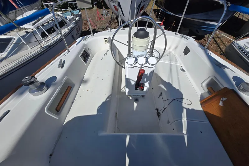 Slide: The Image of 1986 Pearson 303 Sloop cockpit with steering wheel and winches, docked among other boats. - 4