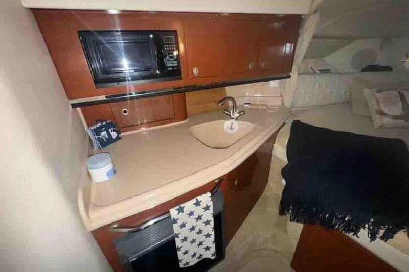 Slide: The Image of 2005 Sea Ray 290 Amberjack cabin with kitchenette, microwave, sink, and cozy sleeping area. - 18