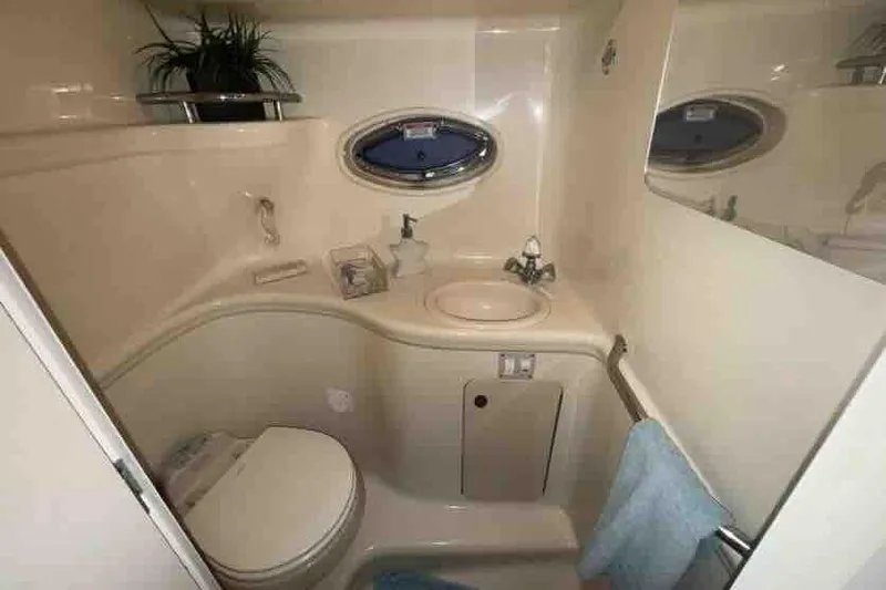Slide: The Image of 2005 Sea Ray 290 Amberjack bathroom with sink, toilet, and porthole window. - 21