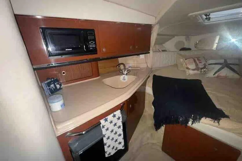 Slide: The Image of 2005 Sea Ray 290 Amberjack cabin interior with kitchenette and cozy sleeping area. - 23
