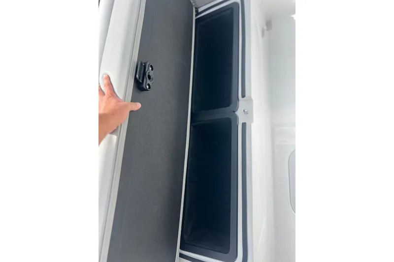 Slide: The Image of 2025 Hurricane Center Console 24 OB storage compartment with hand opening the hatch. - 26