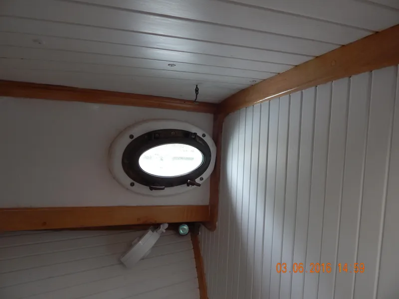 Slide: The Image of Porthole view inside 1997 Webbers Cove PB 26 boat with wooden trim. - 12