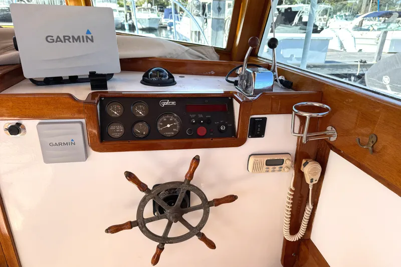 Slide: The Image of 1997 Webbers Cove PB 26 helm with Garmin navigation, steering wheel, and control panel. - 5