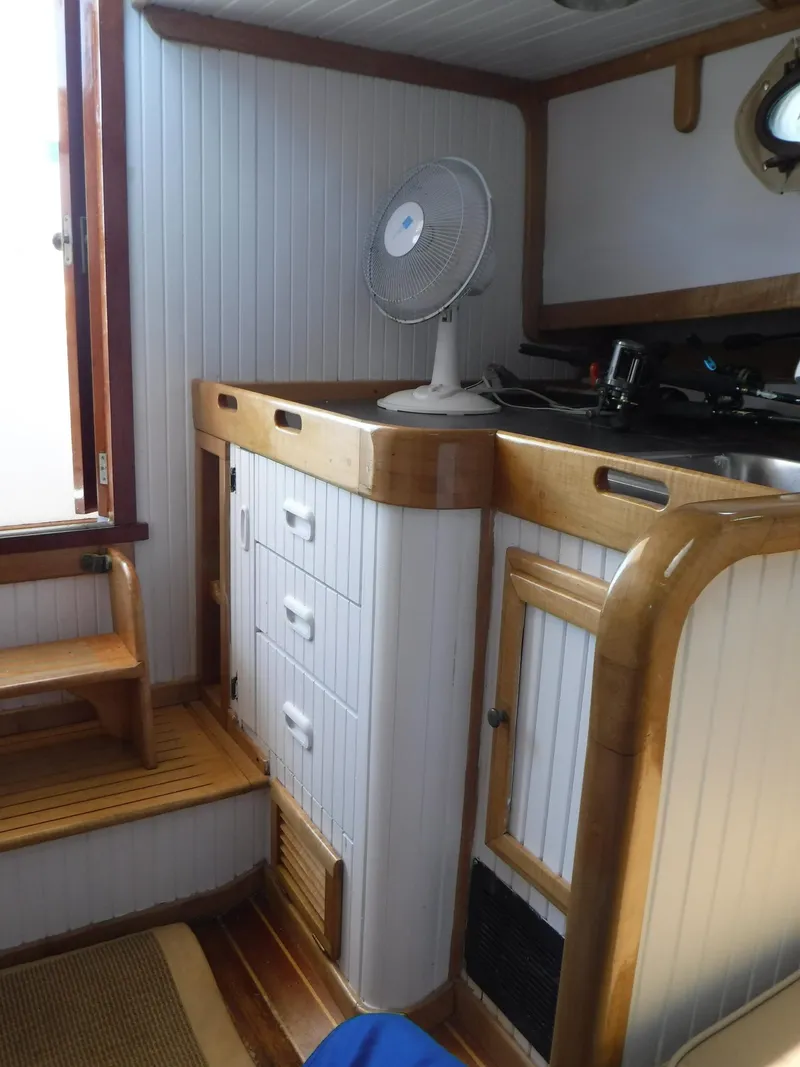 Slide: The Image of Interior of 1997 Webbers Cove PB 26 boat with wooden cabinetry and fan. - 9