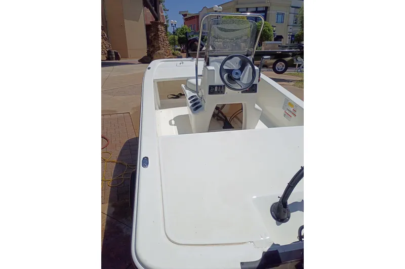 Slide: The Image of 2026 Mako Pro Skiff 13 CC boat with steering console, parked outdoors. - 49
