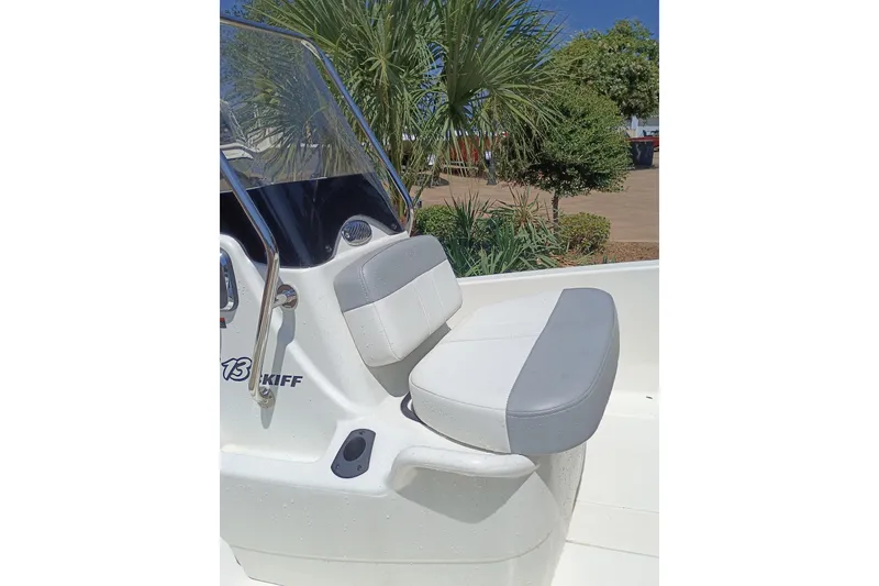 Slide: The Image of 2026 Mako Pro Skiff 13 CC boat with cushioned seating and windshield, surrounded by greenery. - 53
