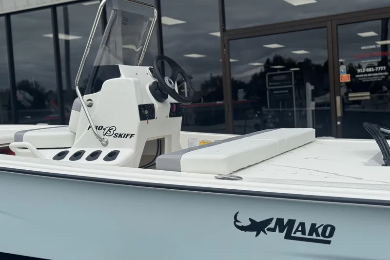 Slide: The Image of 2026 Mako Pro Skiff 13 CC boat with steering console, displayed outdoors. - 45