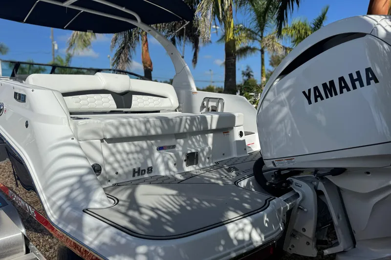 Slide: The Image of 2026 Four Winns HD8 OB boat with Yamaha outboard motor, parked under palm trees. - 15
