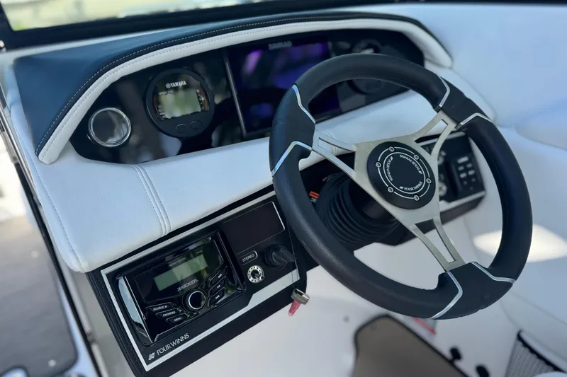 Slide: The Image of 2026 Four Winns HD8 OB boat dashboard with steering wheel and control panel. - 26
