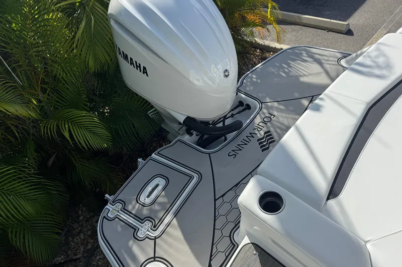 Slide: The Image of 2026 Four Winns HD8 OB boat with Yamaha outboard motor, docked near lush greenery. - 42