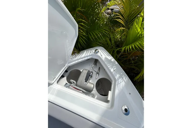 Slide: The Image of Open storage compartment on 2026 Four Winns H9 OB boat, surrounded by lush greenery. - 11