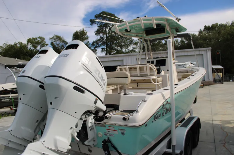 Slide: The Image of 2022 Sea Chaser 24 HFC boat with dual Suzuki engines, parked outdoors. - 2