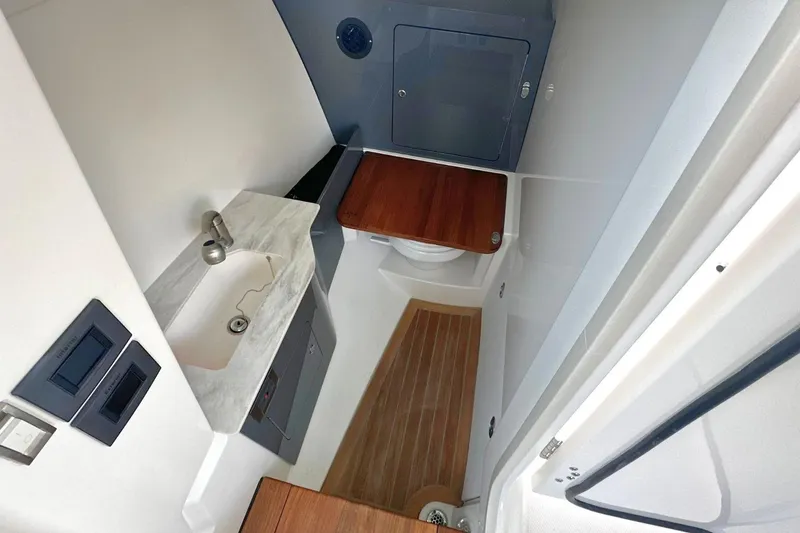 Slide: The Image of 2026 Boston Whaler 330 Vantage boat interior with sink, toilet, and wooden flooring. - 22
