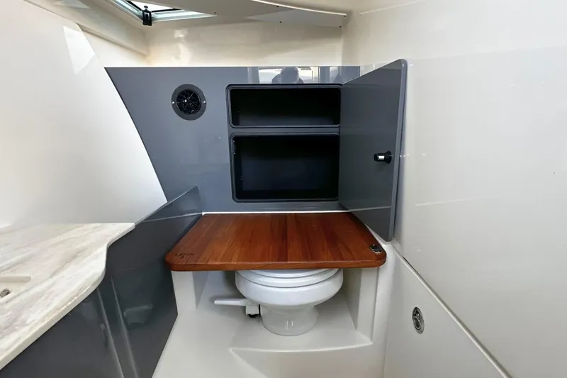 Slide: The Image of 2026 Boston Whaler 330 Vantage boat interior with compact bathroom and wooden countertop. - 23