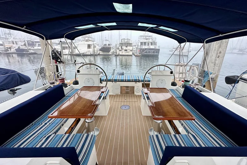 Slide: The Image of 2020 Bavaria C50 yacht interior with striped seating, wooden tables, and marina view. - 29
