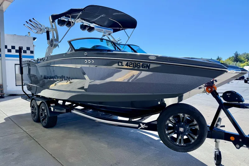 Slide: The Image of 2020 MasterCraft XStar boat on trailer, sleek design, parked outdoors under clear blue sky. - 10