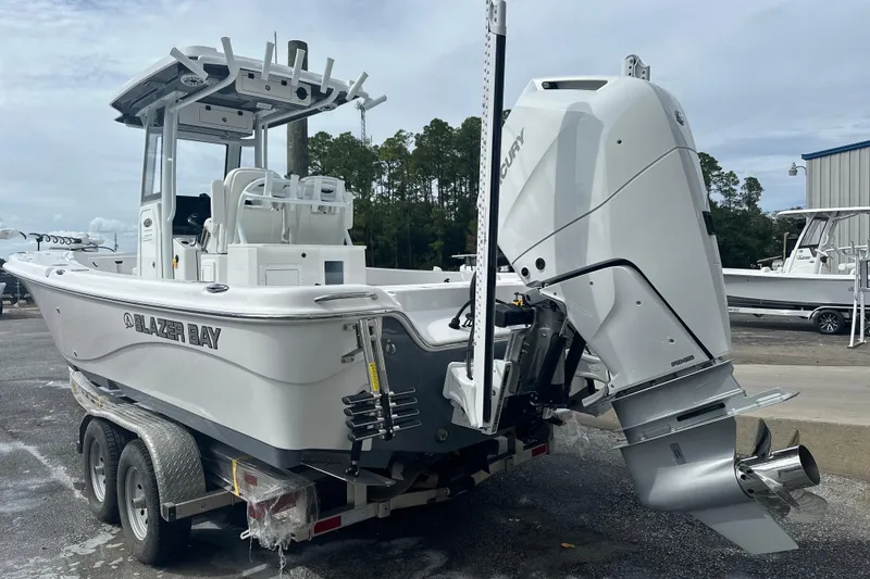 Slide: The Image of 2026 Blazer Bay Makaira 2800 boat on trailer, parked outdoors with trees in background. - 1