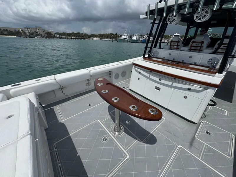Slide: The Image of 2019 HCB 53 Sueños boat deck with seating and rod holders, docked by the water. - 19