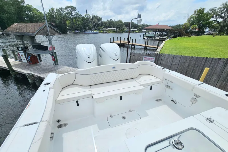 Slide: The Image of 2026 Sea Hunt Ultra 305 SE boat with dual engines docked by a scenic waterfront. - 11