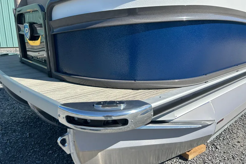 Slide: The Image of 2026 Premier 230 Solaris RF pontoon boat, blue exterior, docked on gravel surface. - 7