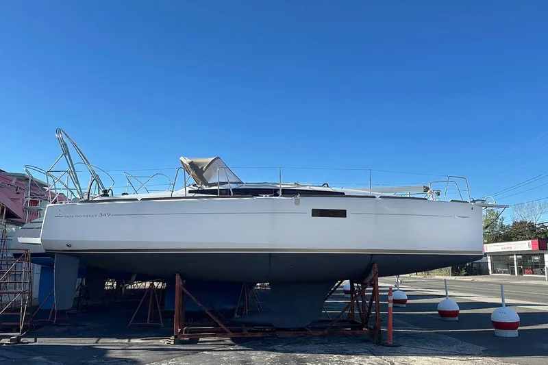 The Image of 2020 Jeanneau Sun Odyssey 349 sailboat on dry dock under clear blue sky. - 0