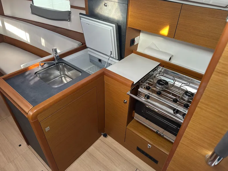 Slide: The Image of Modern kitchen in 2020 Jeanneau Sun Odyssey 349 yacht with sink, stove, and seating area. - 17