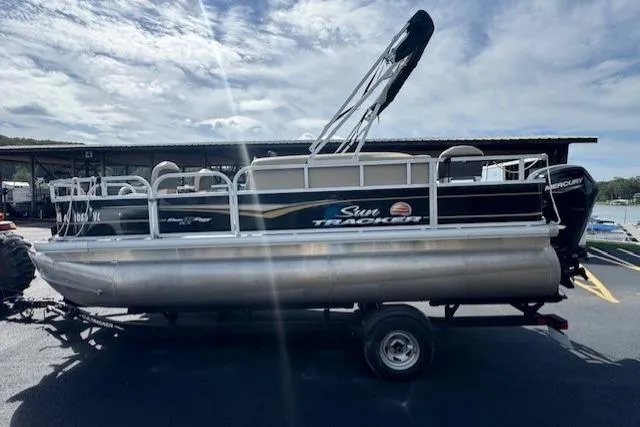 Slide: The Image of 2022 Sun Tracker Bass Buggy 18 DLX pontoon boat on trailer under cloudy sky. - 6