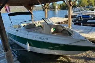 Slide: The Image of 2001 Stingray 240 LS boat docked by a lakeside under a wooden canopy. - 1