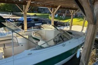 Slide: The Image of 2001 Stingray 240 LS boat docked under wooden shelter, green and white exterior. - 3