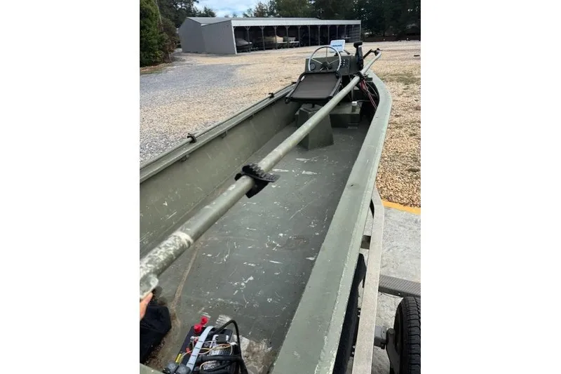 Slide: The Image of 2018 Encore Boat Works 18, green interior, parked on gravel near storage sheds. - 11