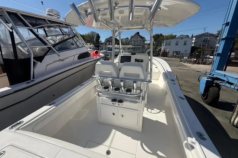 Slide: The Image of 2017 Regulator 25 boat interior with seating and console, docked beside another vessel. - 14