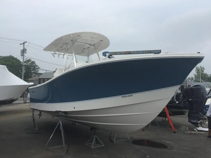 Slide: The Image of 2017 Regulator 25 boat with blue hull on stands in a marina. - 18