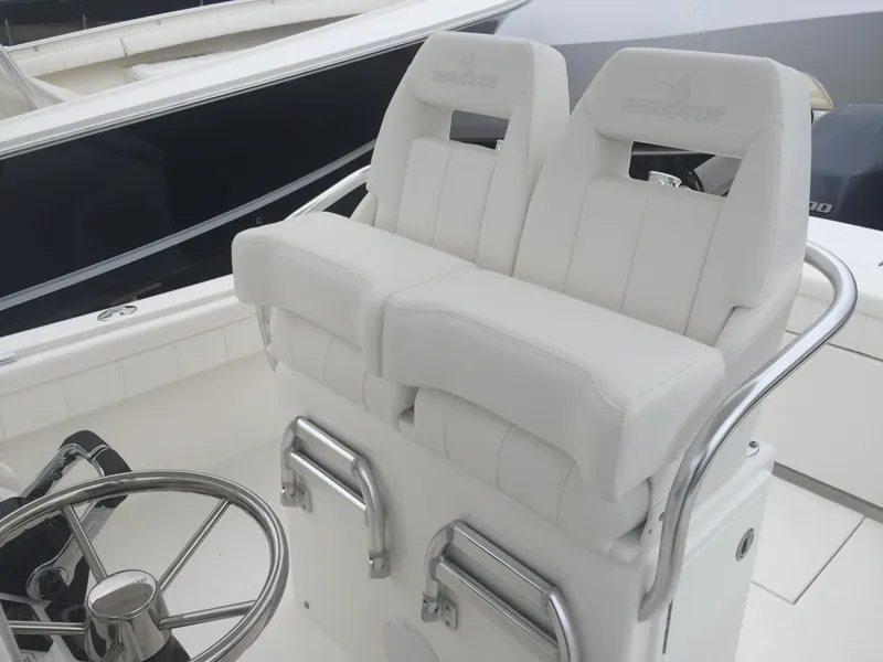 Slide: The Image of 2017 Regulator 25 boat with white cushioned helm seats and stainless steel accents. - 2