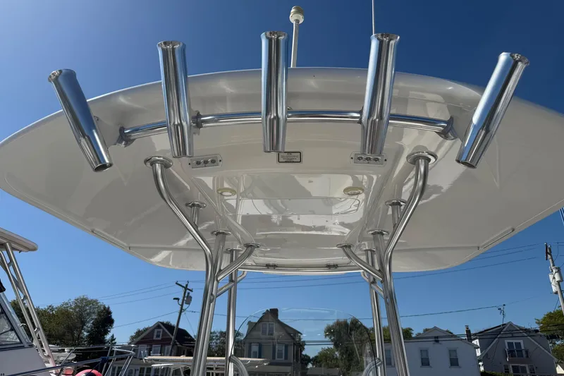 Slide: The Image of 2017 Regulator 25 boat with T-top and rod holders under clear blue sky. - 34