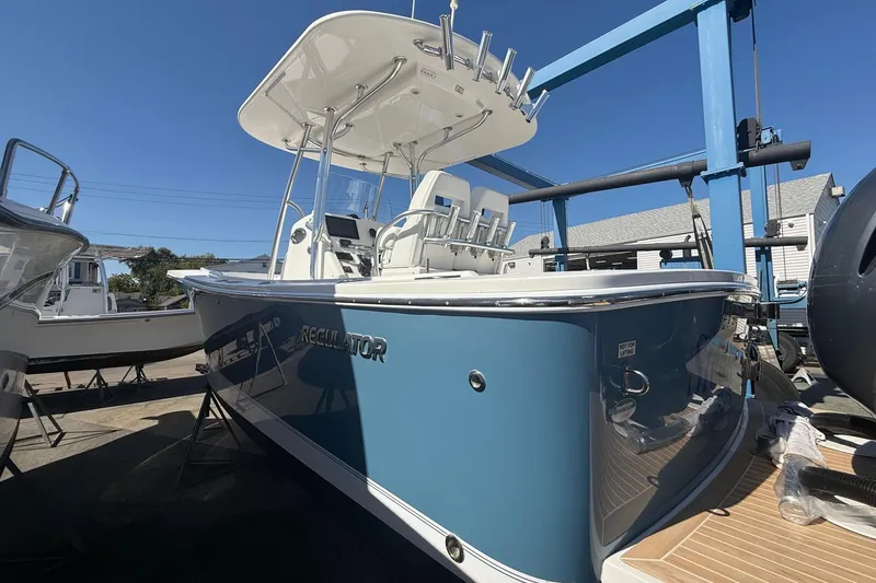 Slide: The Image of 2017 Regulator 25 boat with blue hull, docked under clear sky. - 4