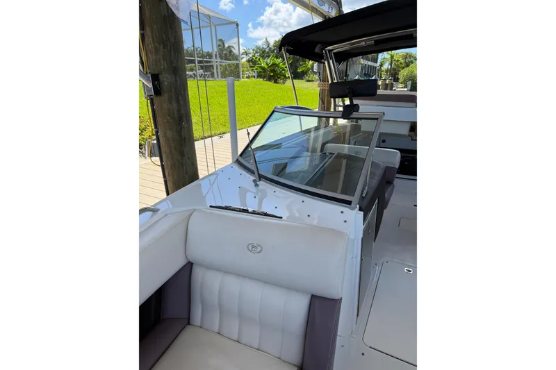 Slide: The Image of 2010 Cobalt 296 boat interior with white seating and glass windshield, docked under sunny skies. - 16