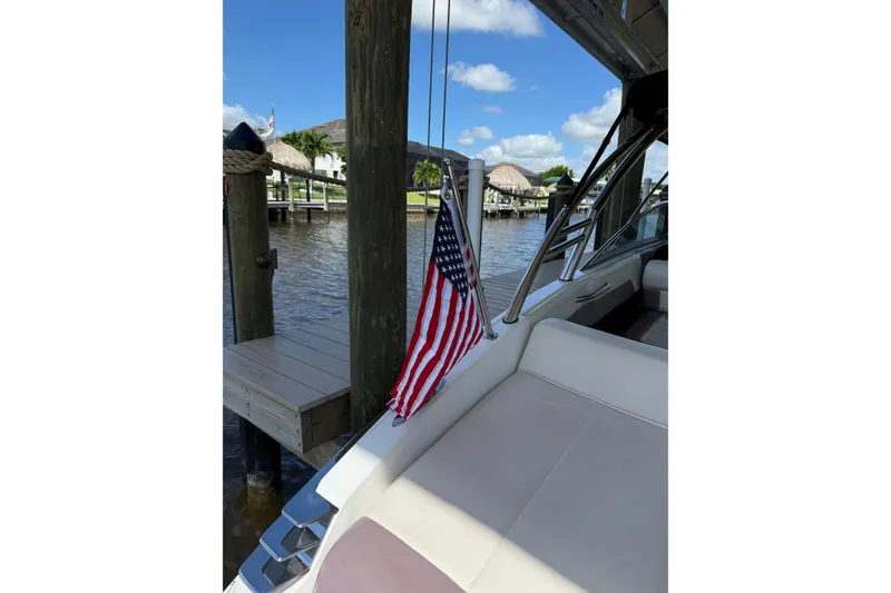 Slide: The Image of 2010 Cobalt 296 boat docked with American flag, sunny day, waterfront view. - 46