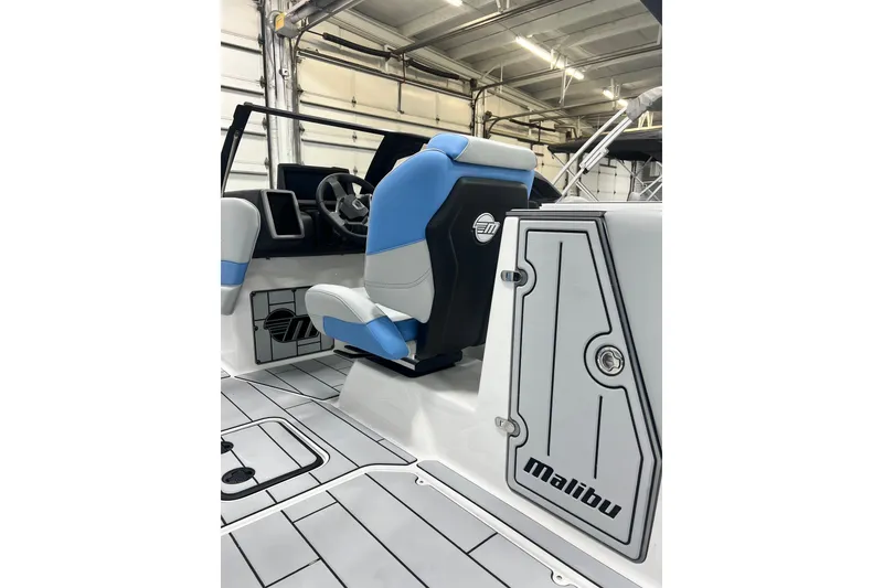 Slide: The Image of 2024 Malibu Wakesetter 24 MXZ interior with blue and white seating in a garage. - 11