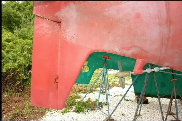 Slide: The Image of 1971 Nautor Swan 43 Sloop hull and propeller on stands, surrounded by greenery. - 14
