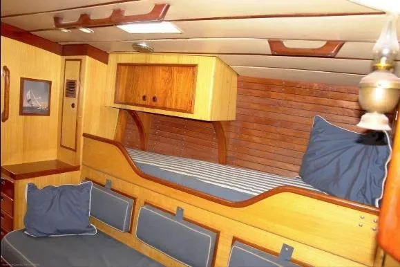 Slide: The Image of Interior of 1971 Nautor Swan 43 Sloop, featuring wooden cabinetry and cozy bedding. - 4