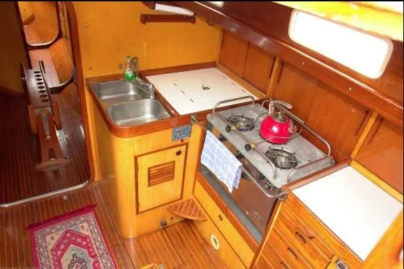 Slide: The Image of Interior of 1971 Nautor Swan 43 Sloop, featuring a compact wooden kitchen with stove and sink. - 8