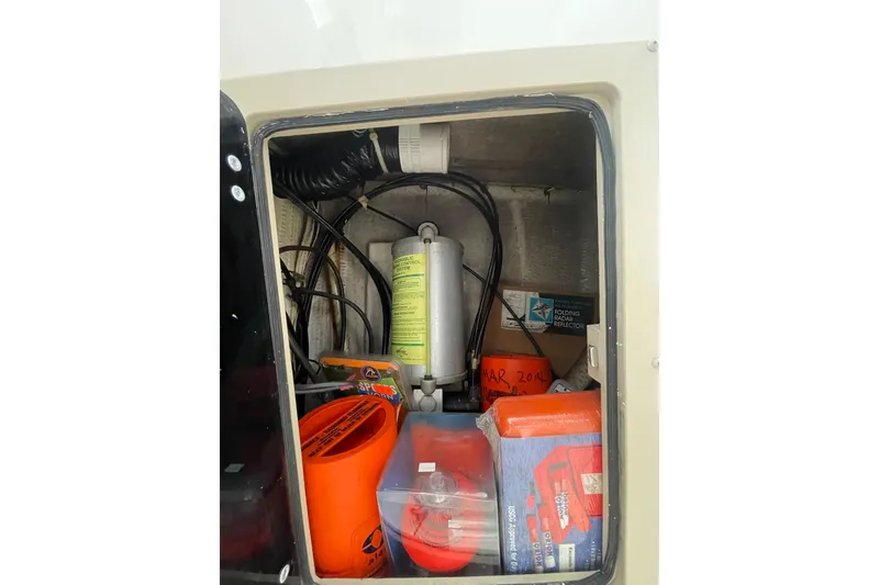 Slide: The Image of Storage compartment of a 1999 Albemarle 30 boat with safety equipment and supplies. - 12