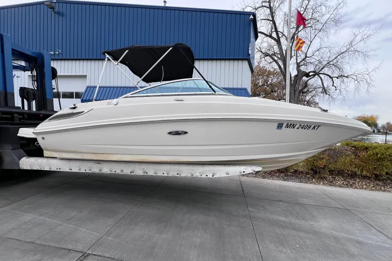 The Image of 2010 Sea Ray 220 Sundeck boat on a lift, near a blue building. - 0