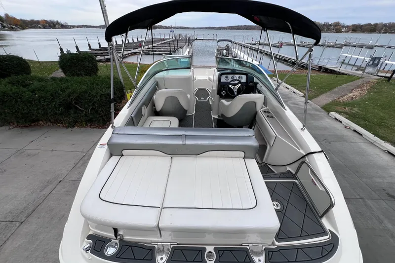 Slide: The Image of 2010 Sea Ray 220 Sundeck boat with spacious seating, docked by a serene lake. - 10
