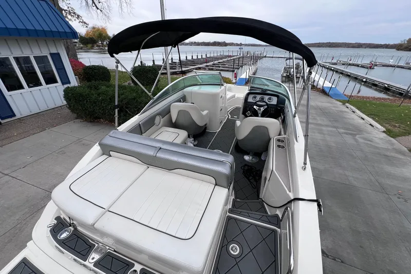 Slide: The Image of 2010 Sea Ray 220 Sundeck boat docked near a marina with canopy and seating. - 11