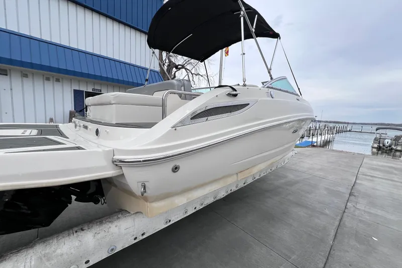 Slide: The Image of 2010 Sea Ray 220 Sundeck boat docked near a marina, featuring sleek design and canopy. - 2