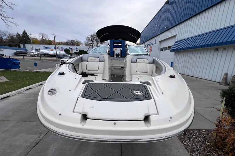 Slide: The Image of 2010 Sea Ray 220 Sundeck boat displayed outdoors near a blue building. - 22